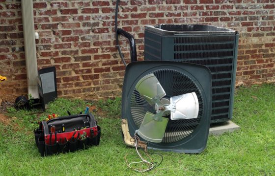 homeguide-hvac-air-conditioner-compressor-and-condensor-coil-with-fan-and-tools-being-repaired